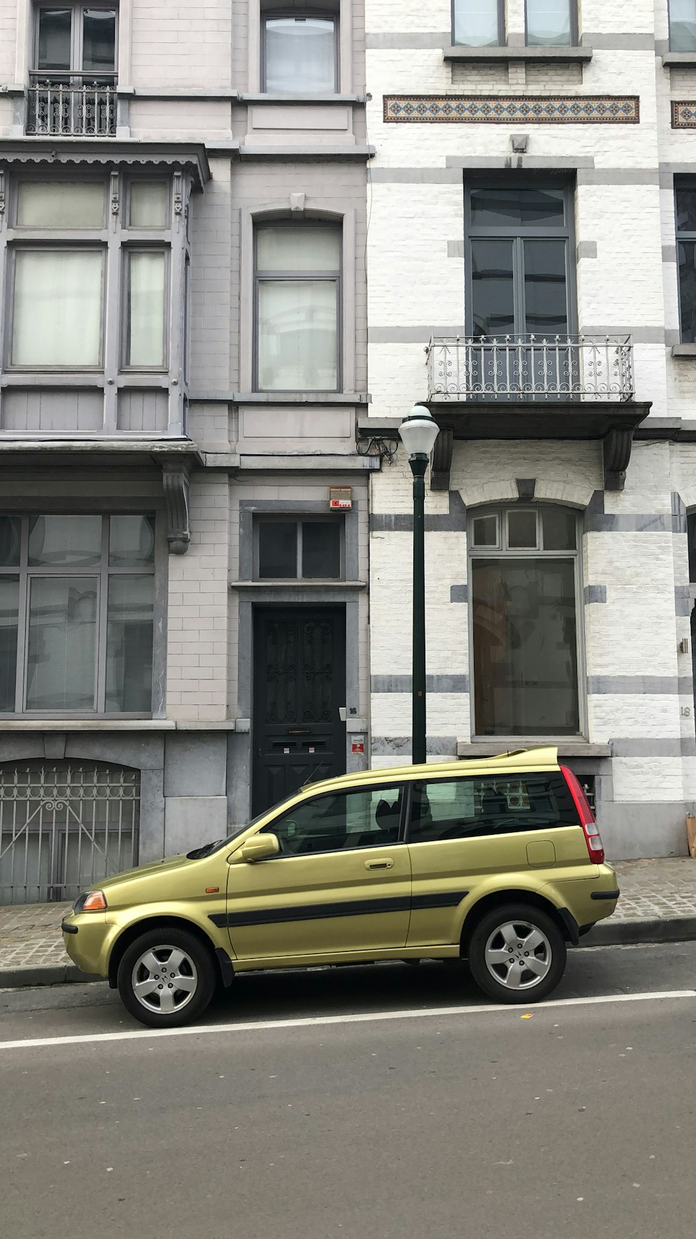 hatchback amarelo de 3 portas estacionado ao lado do edifício de concreto cinza durante o dia