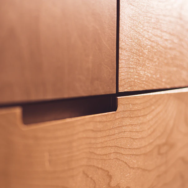 A close-up view of wooden drawers with a natural, smooth finish. The grain pattern is visible on the surface, contributing to the texture and warmth of the wood.