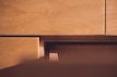 Wooden surfaces of plywood sheets are closely stacked with visible grain patterns and layered textures. The light casts a warm glow, highlighting the natural wood tones.