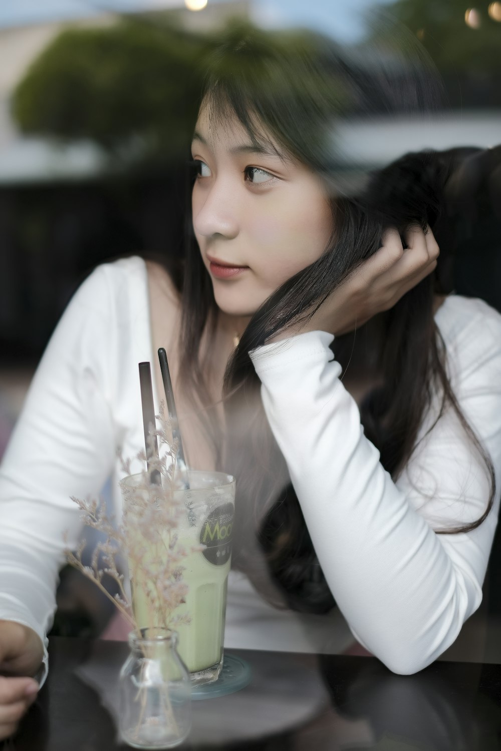 woman in white long sleeve shirt holding clear drinking glass