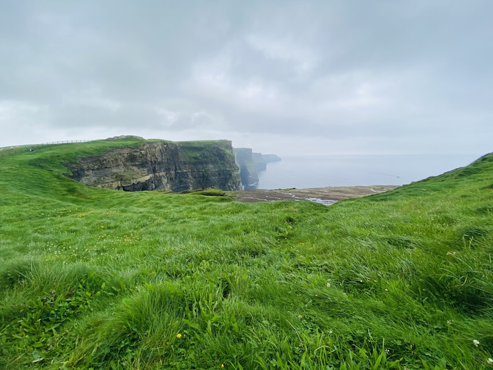 green grass field under cloudy sky during daytime