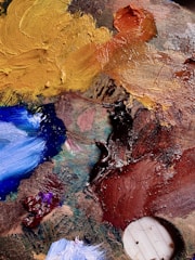 Close-up of textured paint samples in various earthy tones on a palette