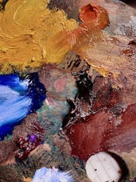 Close-up of an oil painting palette with thick, textured brushstrokes in warm tones.