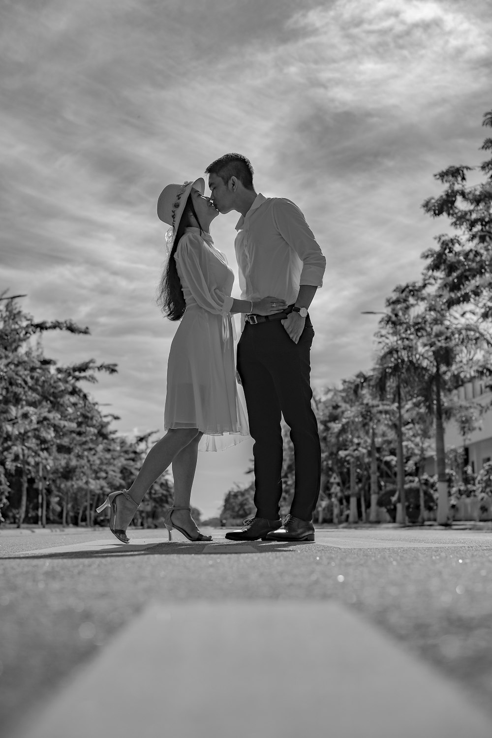 hombre y mujer besándose en la carretera en fotografía en escala de grises