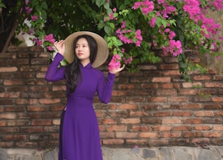 woman in purple long sleeve dress standing beside purple flowers