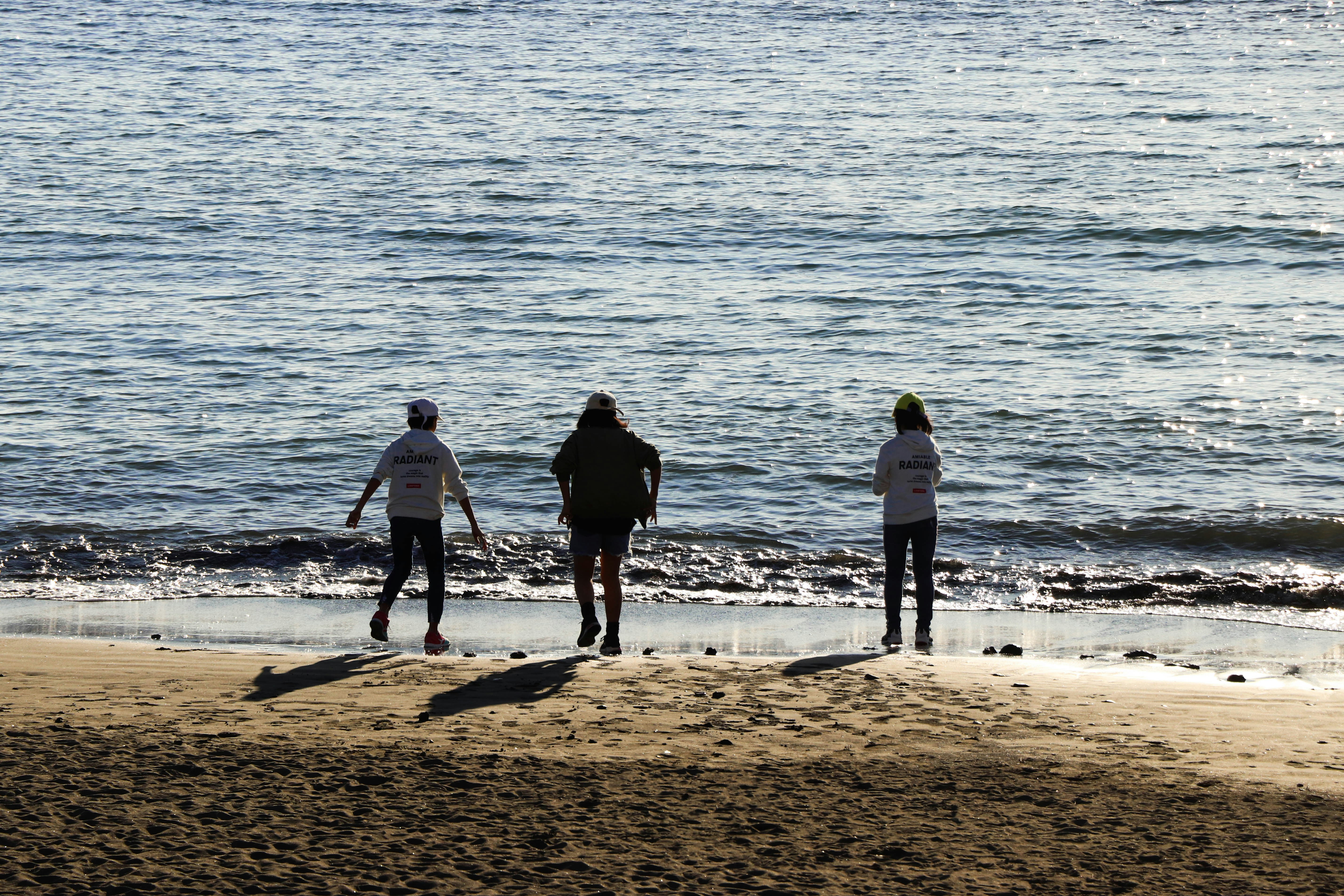 3 men standing on beach during daytime