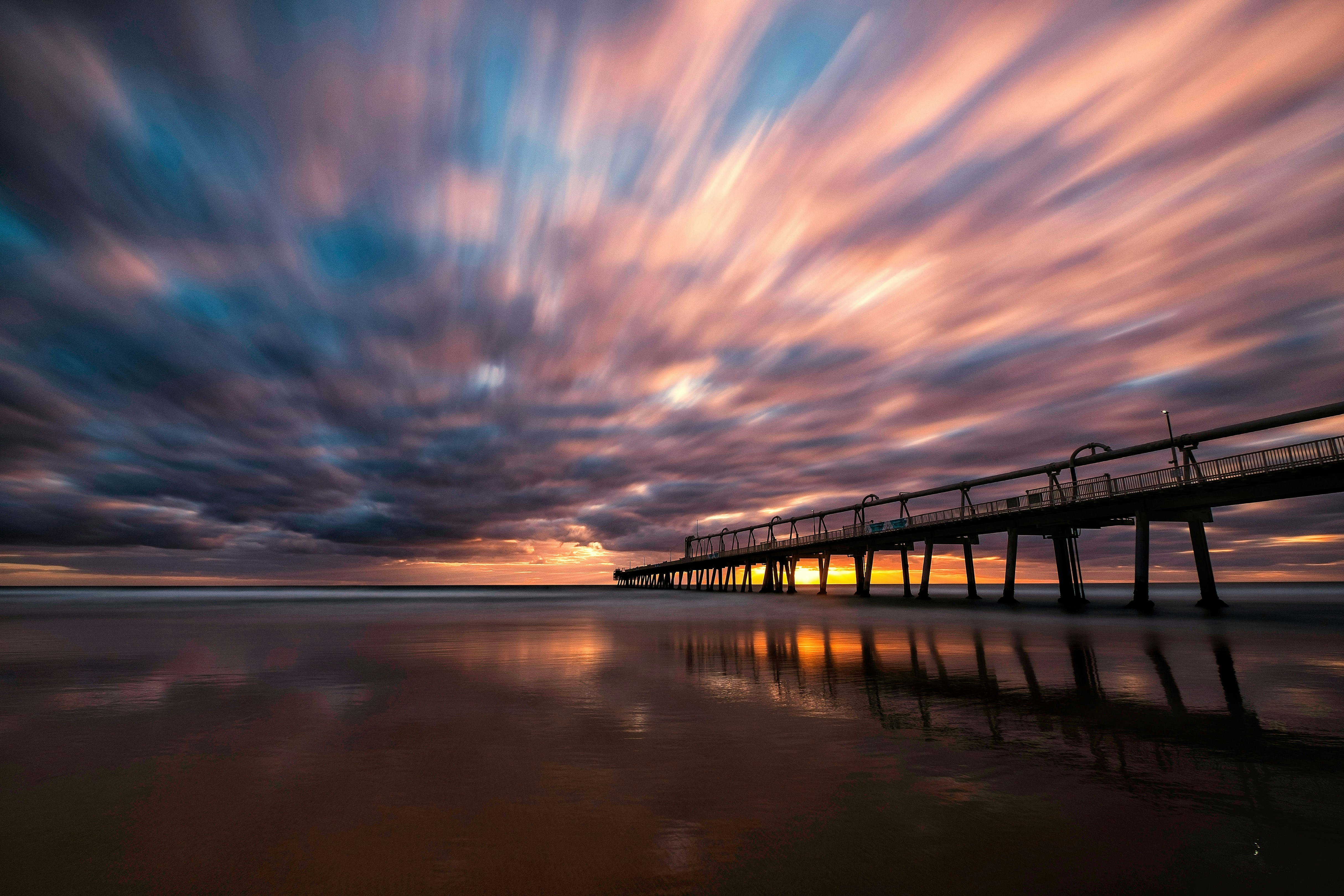 brown wooden dock on body of water during sunset
