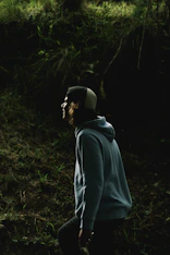 man in gray hoodie standing in forest during daytime
