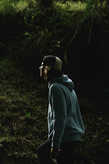 man in gray hoodie standing in forest during daytime
