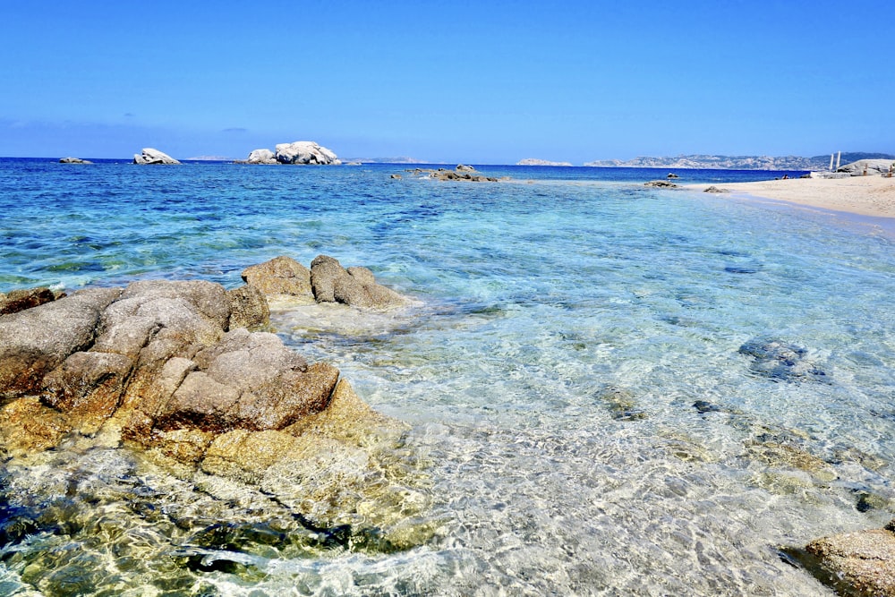 Rocce marroni sul mare blu sotto il cielo blu durante il giorno