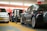 Several electric cars are charging in an indoor parking garage. The space is brightly lit with predominant red and white colors in the background. Charging cables are connected to the cars, highlighting a modern and technological atmosphere.