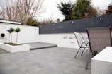 A modern patio area featuring stone tiles and lush green plants surrounding a cozy seating space.