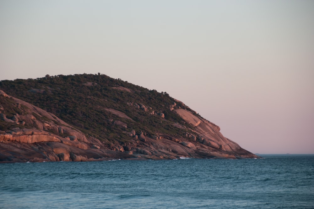 brown and green mountain beside body of water during daytime