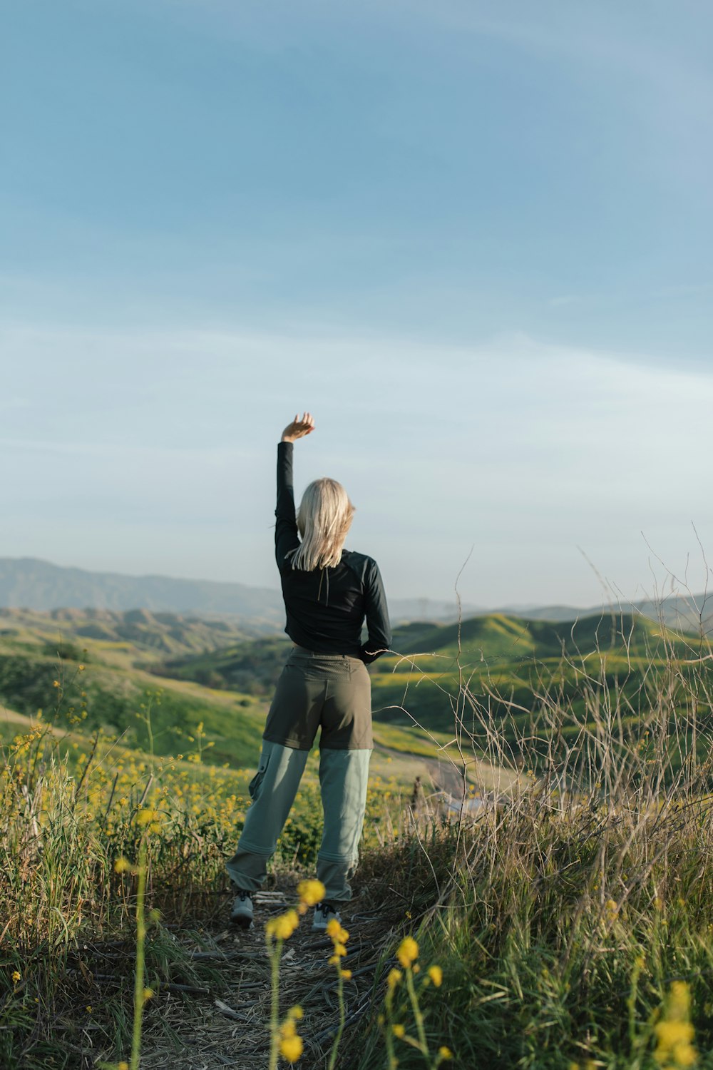 woman in black long sleeve shirt and blue denim jeans standing on green grass field during