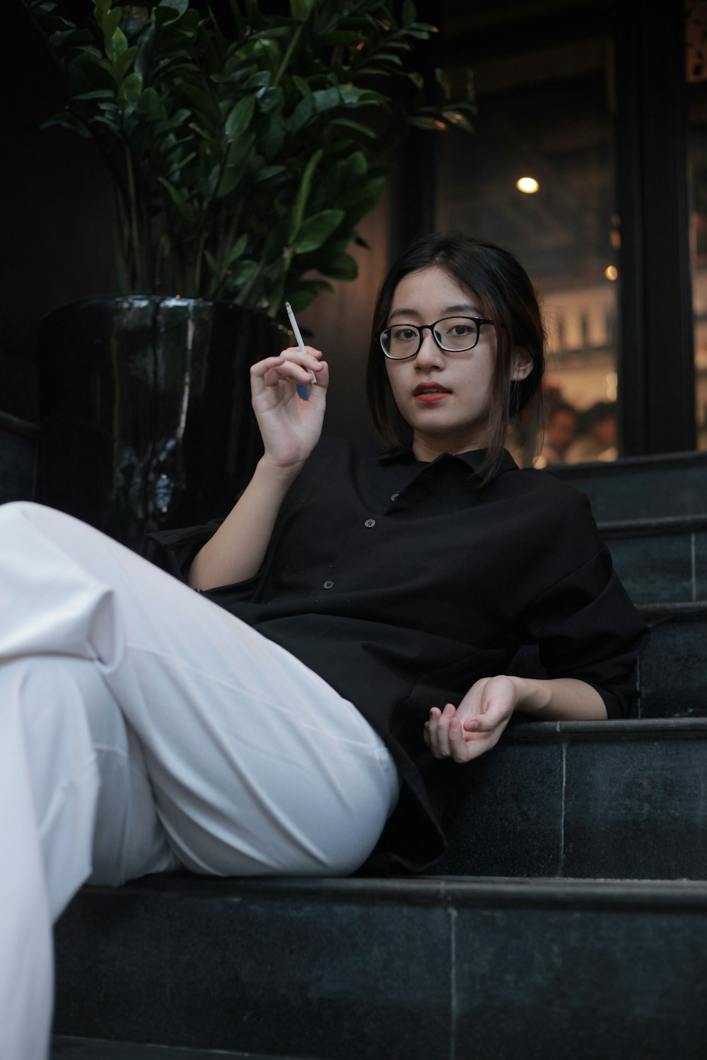 woman in black long sleeve shirt and white pants sitting on black chair