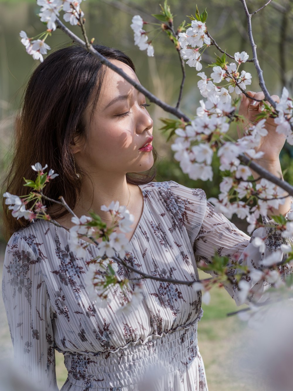 woman in white and black floral dress holding white flowers