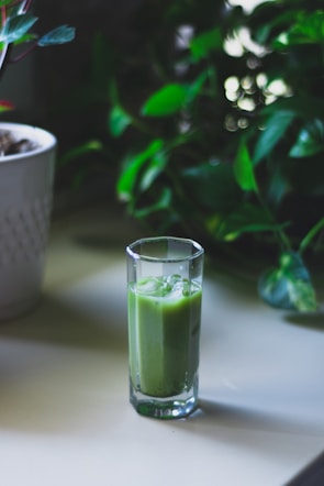 Refreshing glass of green smoothie made with kale, apple, and lemon on a wooden table.