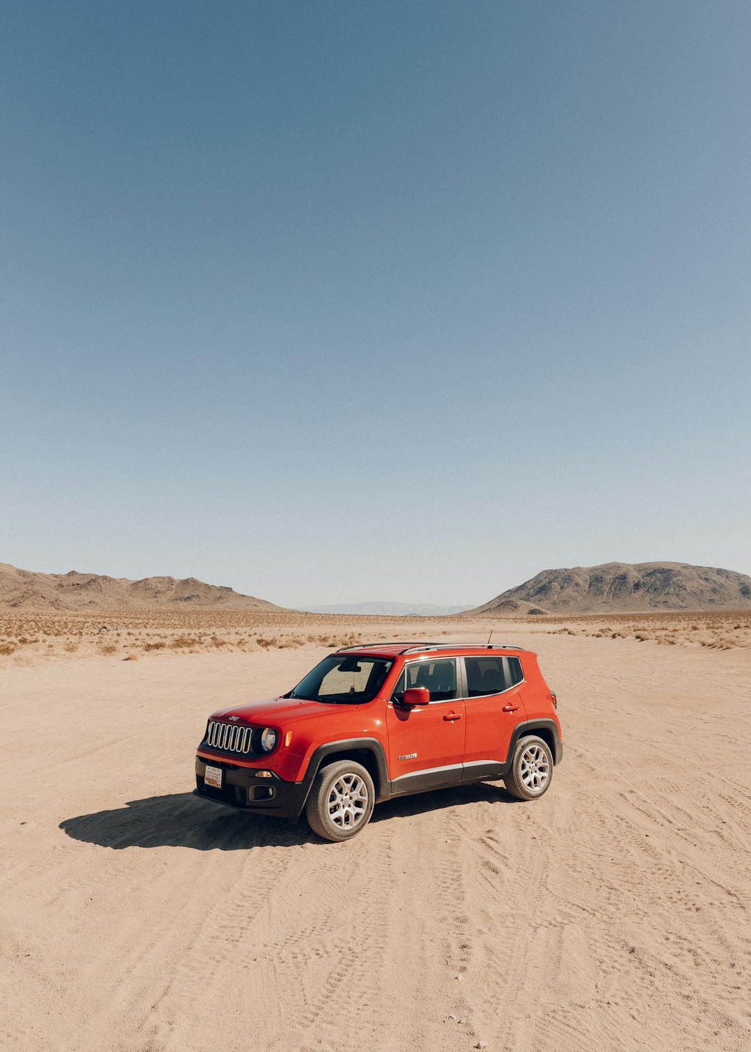 red suv on brown sand under blue sky during daytime
