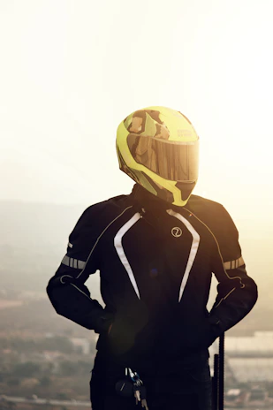 Close-up of a bright yellow matte motorcycle helmet resting on a black motorbike seat under natural sunlight.