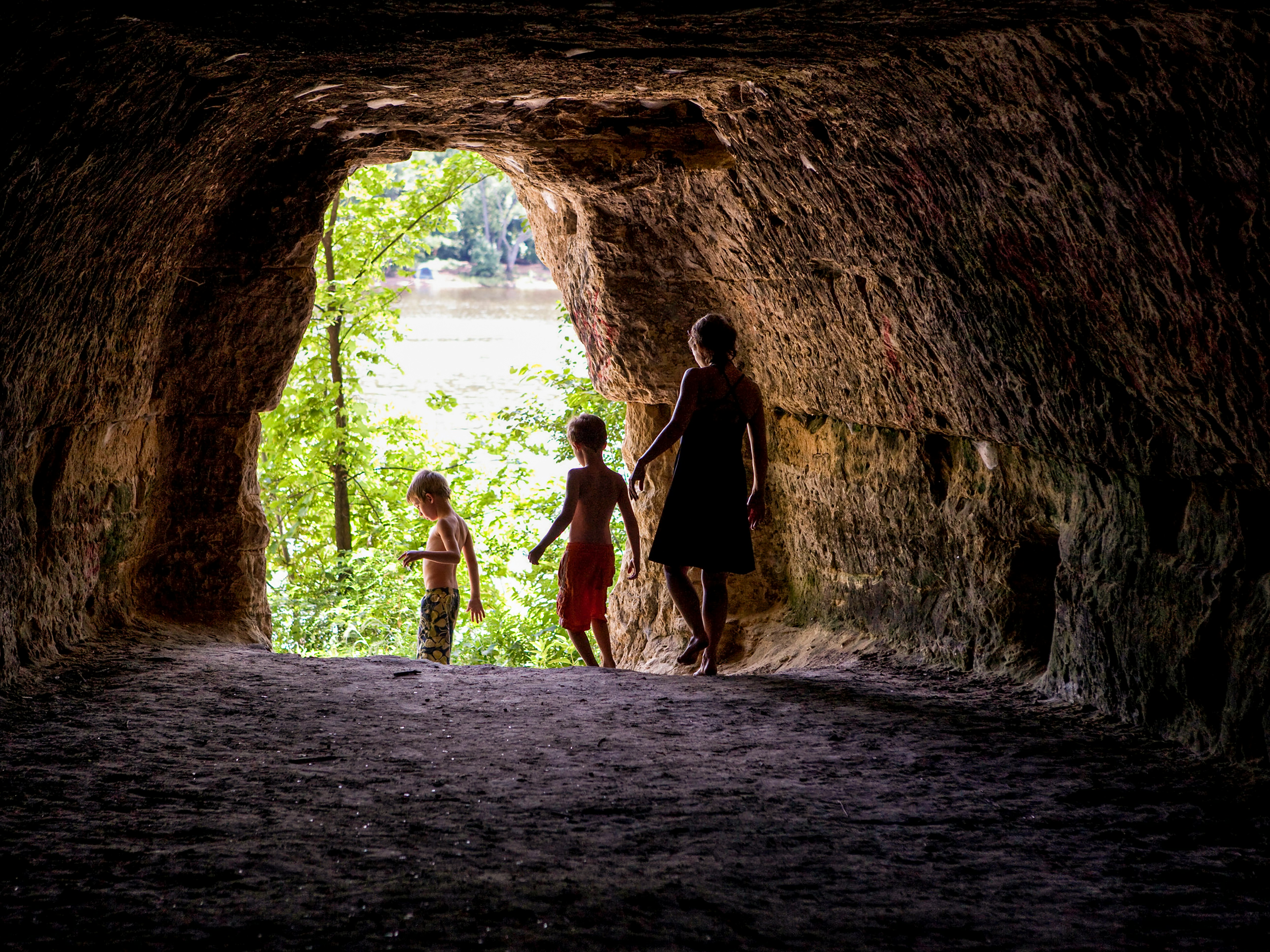 2 women in black dress walking on brown tunnel during daytime