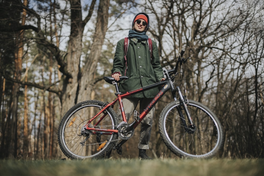 man in green jacket riding on red and black mountain bike