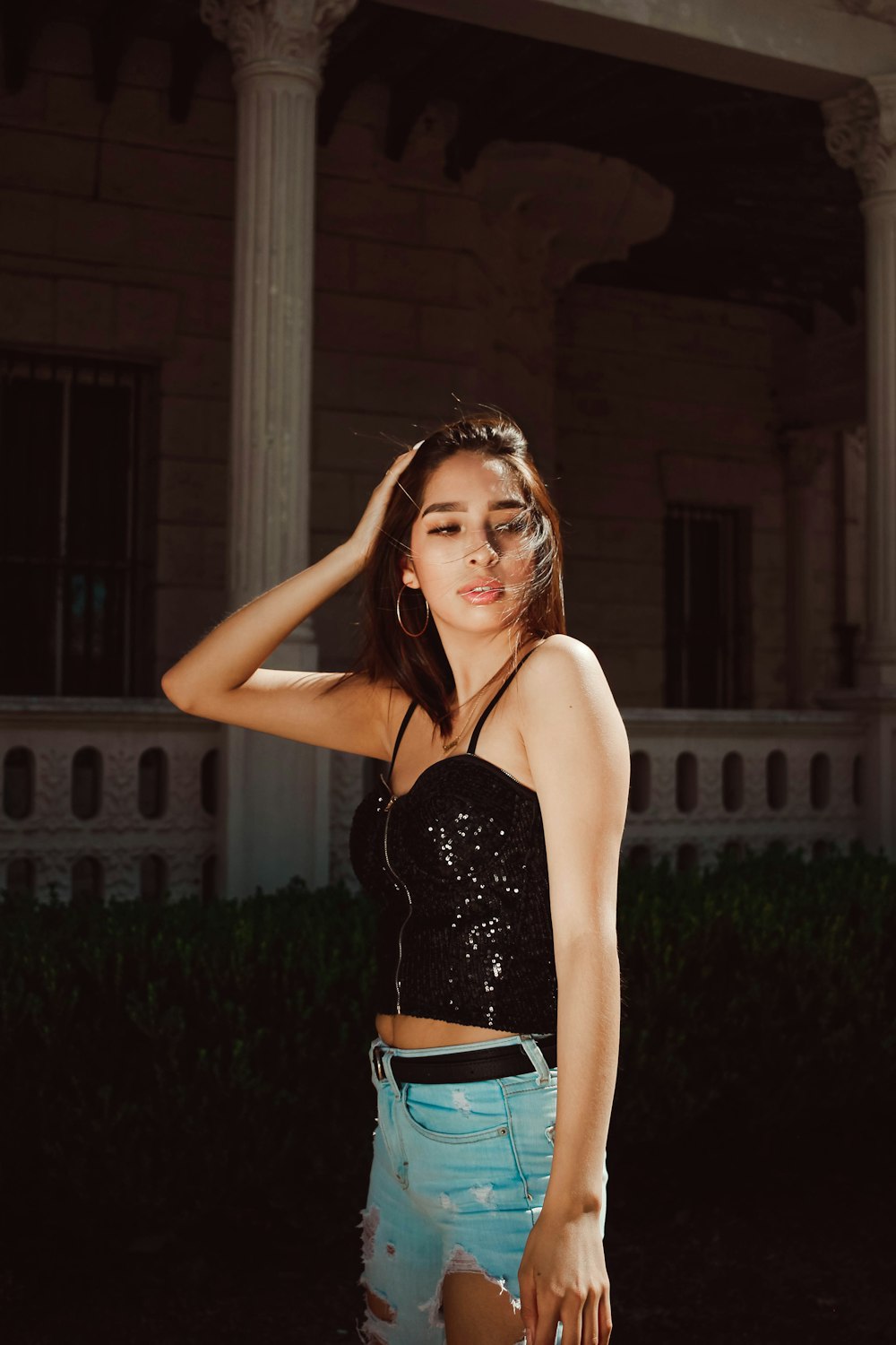 woman in black spaghetti strap top and blue denim daisy dukes standing near brown wooden house