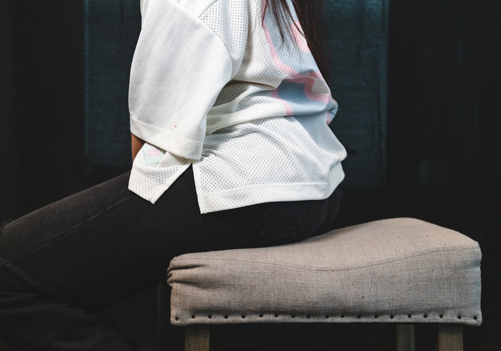 person in white shirt and black pants sitting on brown chair