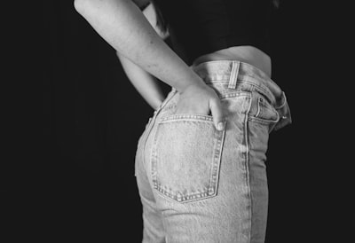 grayscale photo of woman in black tank top and denim jeans saturated teams background