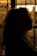 A silhouette of a person with curly hair against a warm, glowing sunset backdrop. The light filters through what appears to be a window with intricate ironwork.