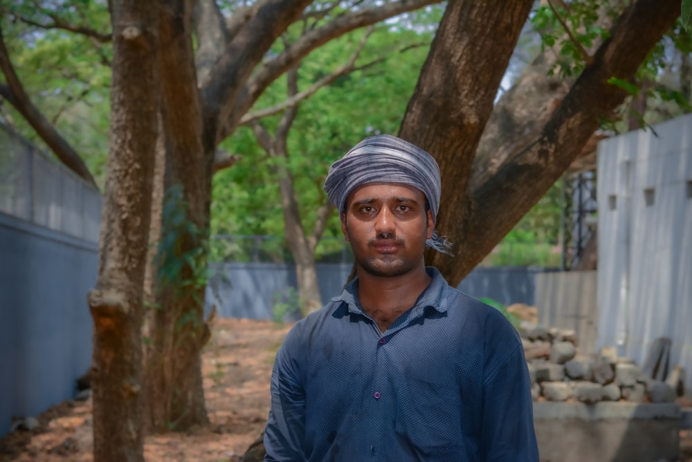 man in blue dress shirt standing near tree