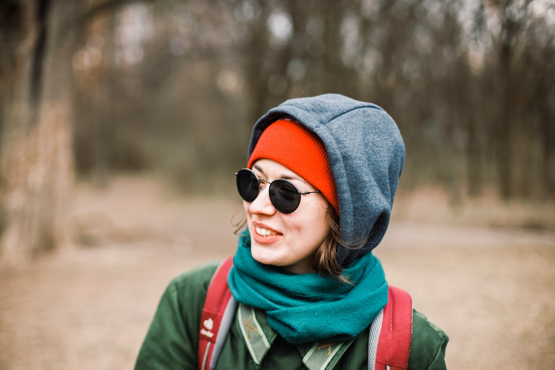 woman in green jacket wearing blue knit cap and sunglasses