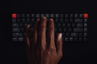Close-up of hands typing on a keyboard with black background and marketing notes.