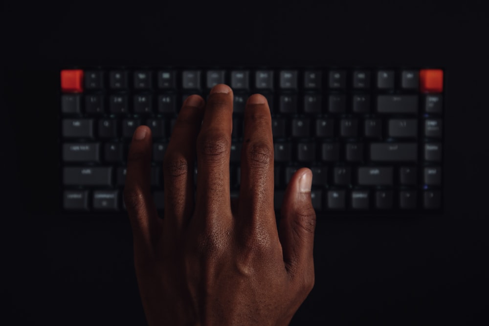 黒いコンピュータのキーボードに手を置く人
