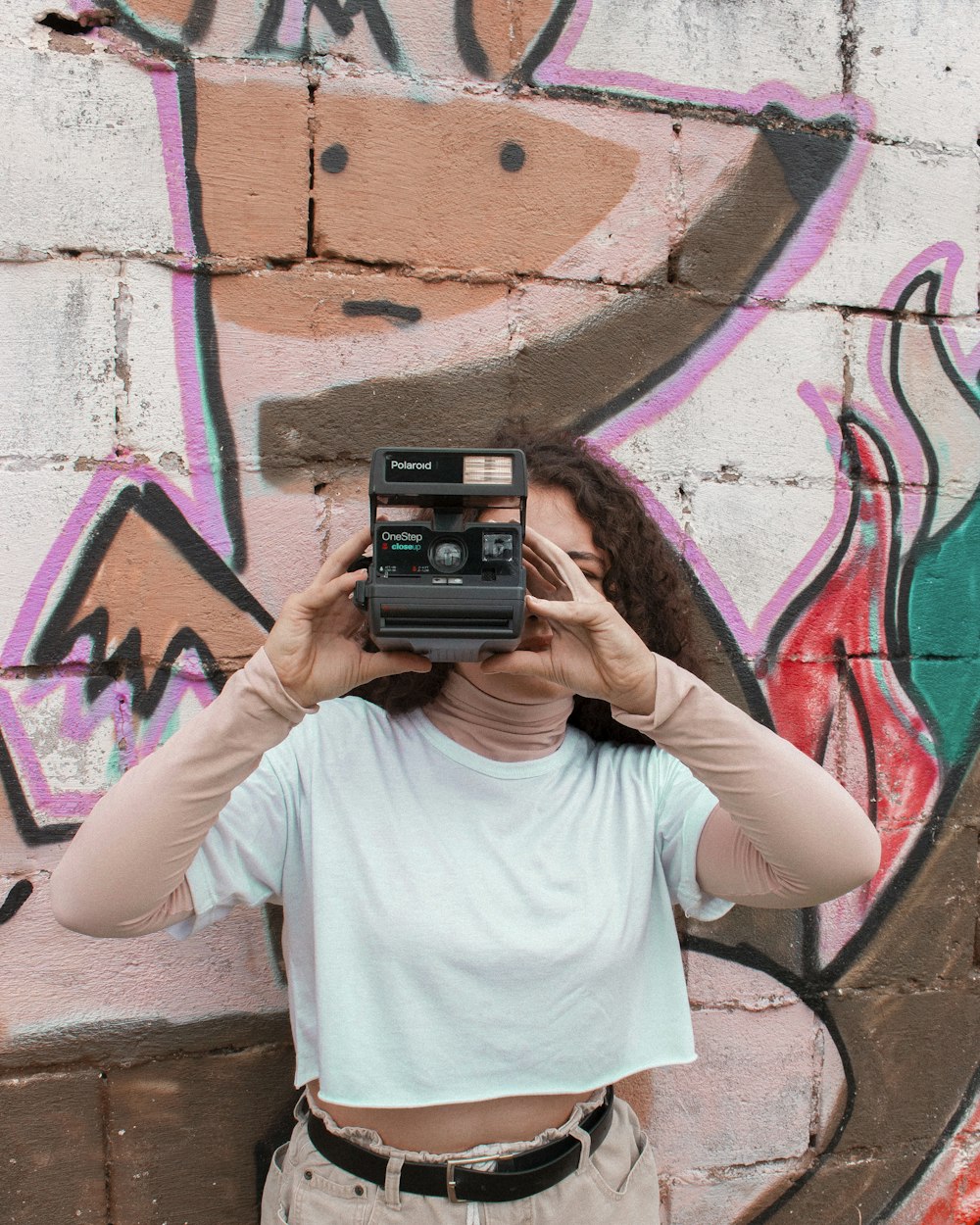 Femme en T-shirt blanc à col rond tenant un appareil photo noir