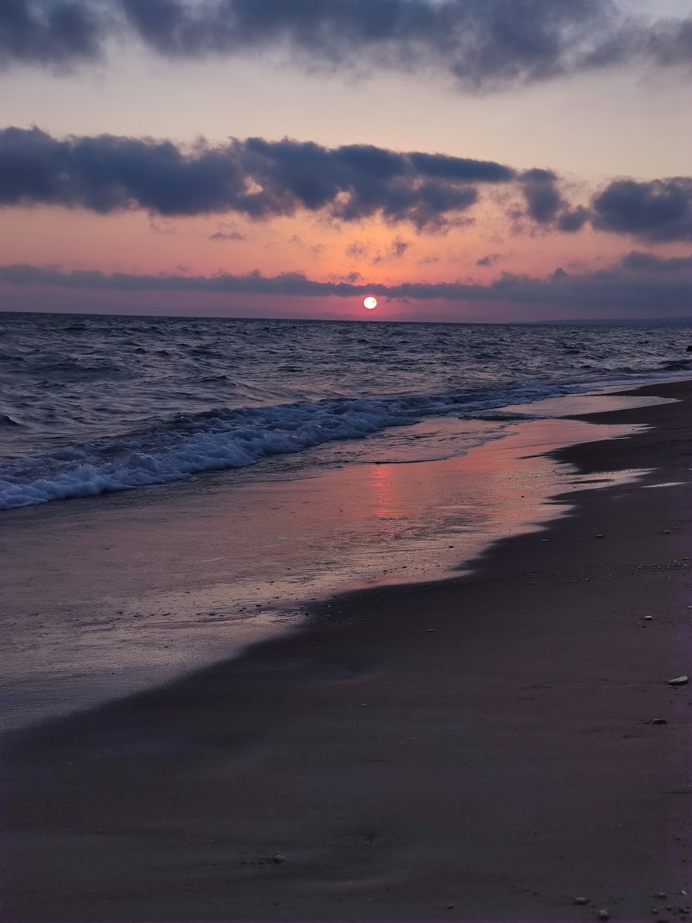 sea waves crashing on shore during sunset