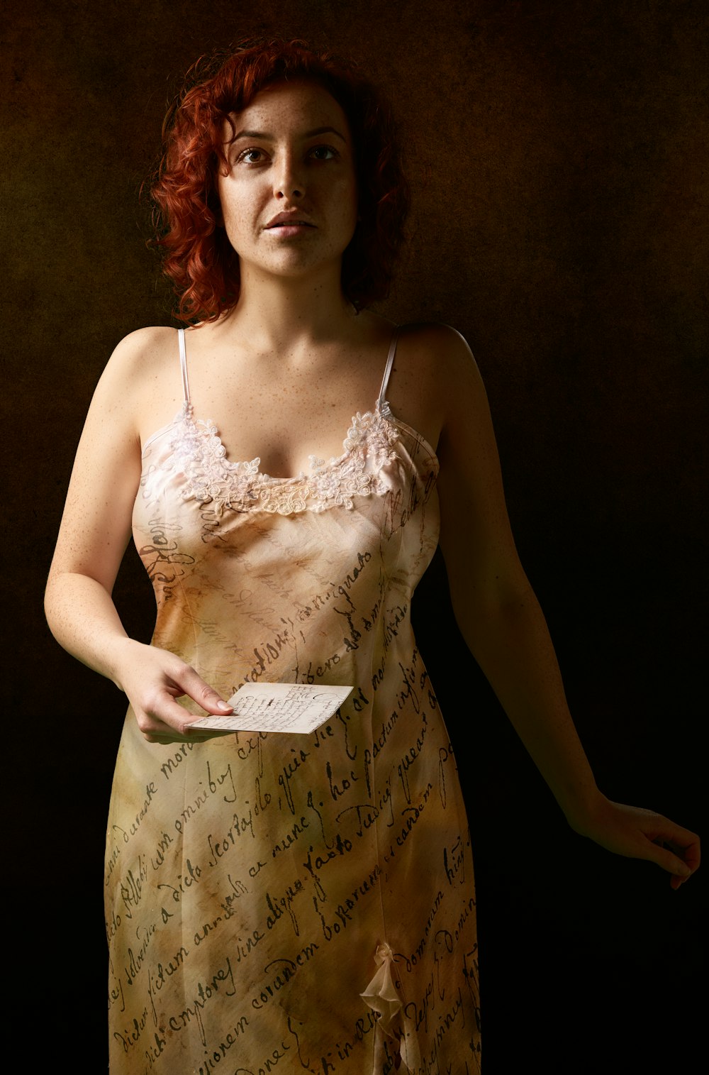 Femme en robe blanche à bretelles spaghetti tenant du papier blanc