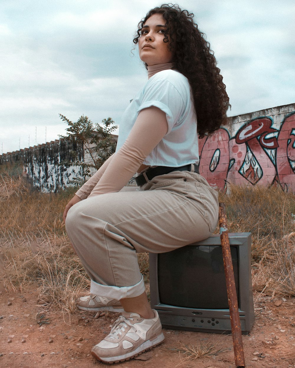 woman in white t-shirt and gray pants sitting on brown wooden seat