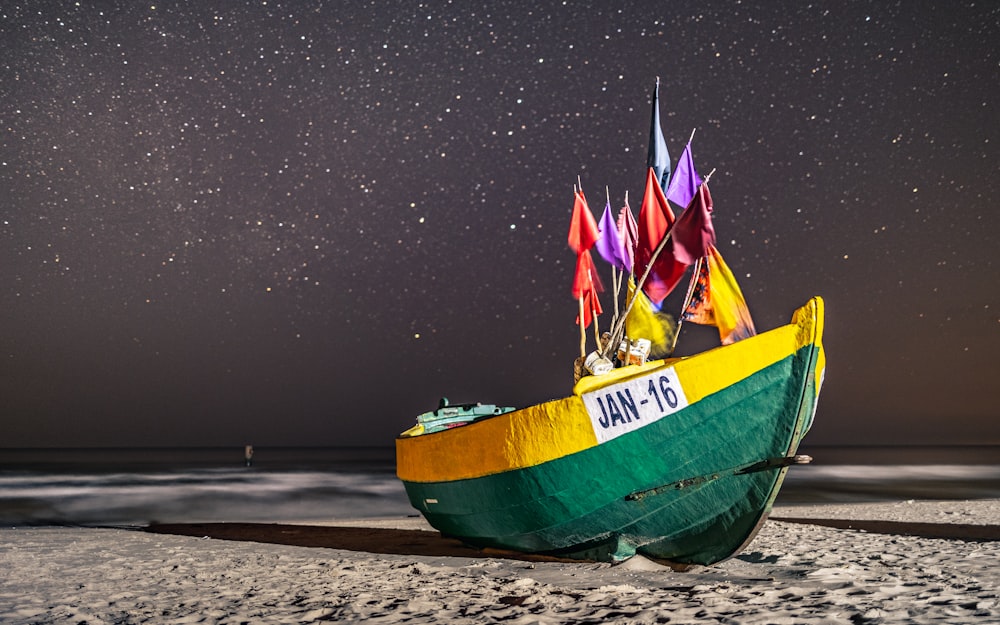 green and yellow boat on beach shore during night time