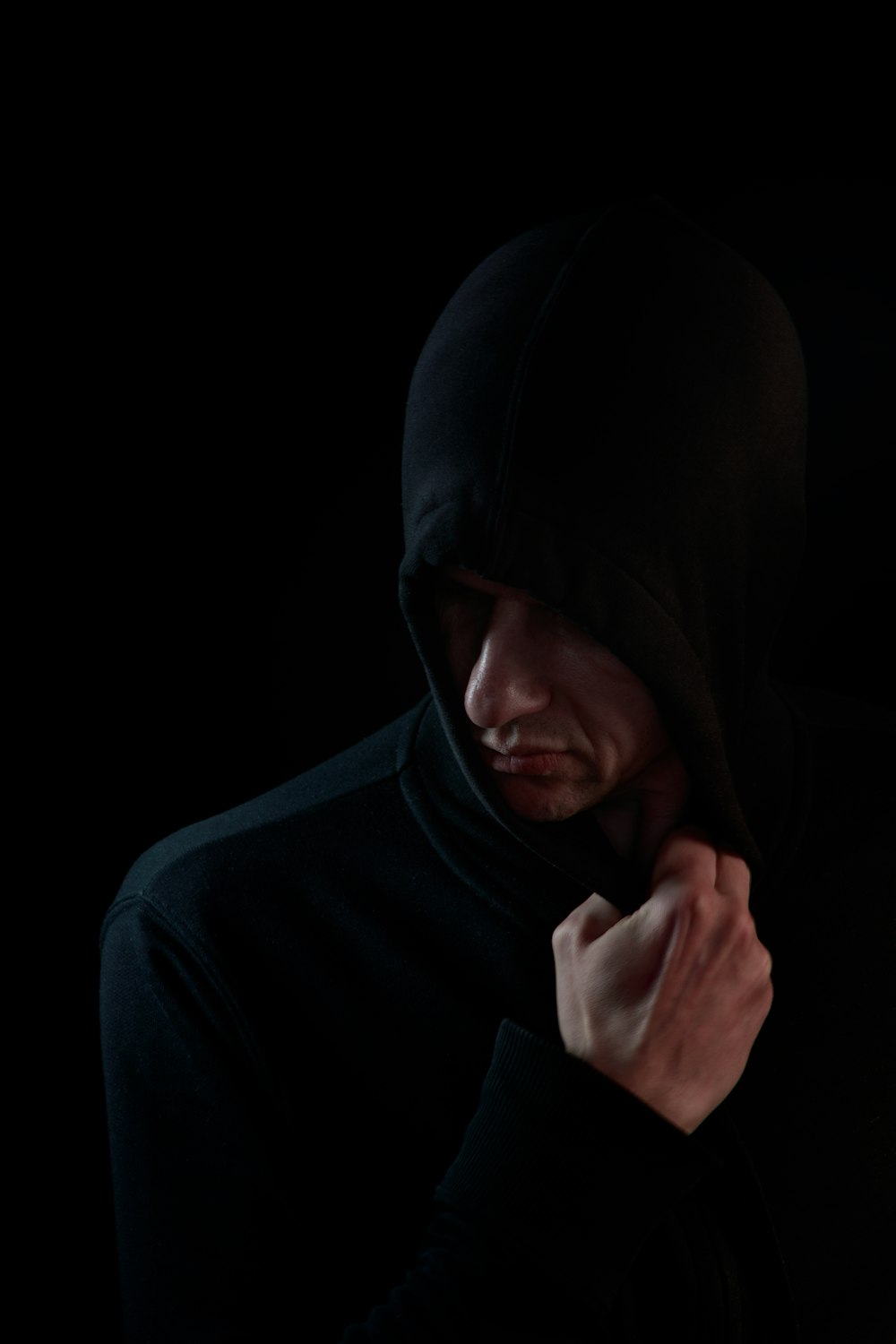 man in black hoodie covering his face