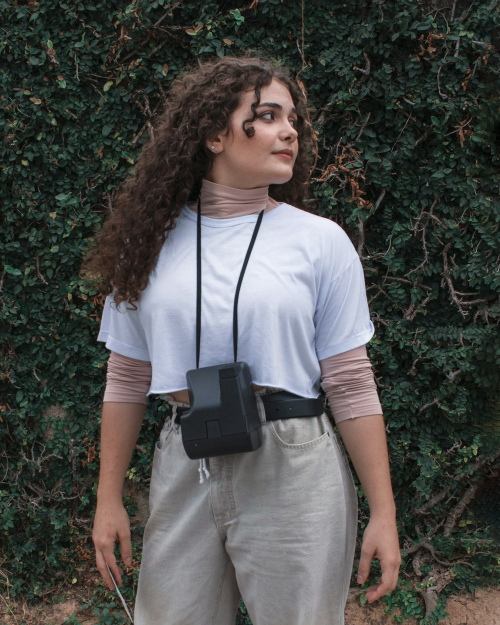 woman in white crew neck t-shirt and gray denim jeans standing beside green plant