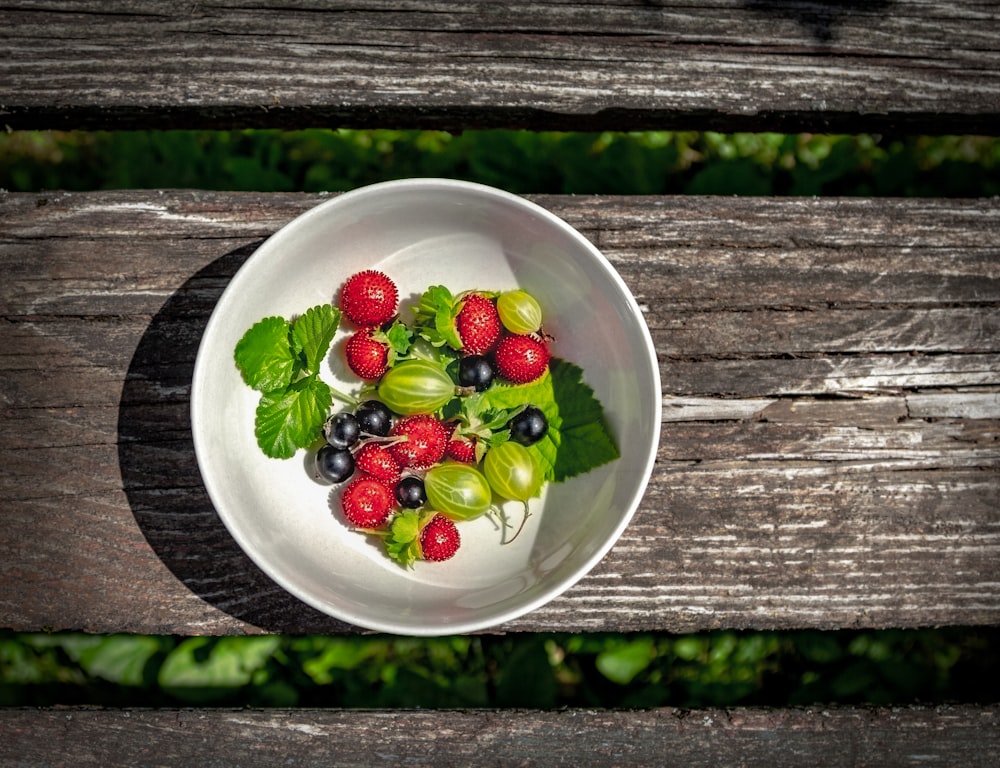 red and green fruits on white ceramic bowl