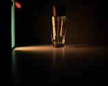 Sophisticated perfume bottle placed on a textured dark surface with soft glowing light.