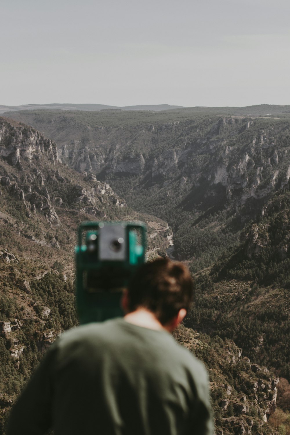 man in gray hoodie standing on rocky mountain during daytime