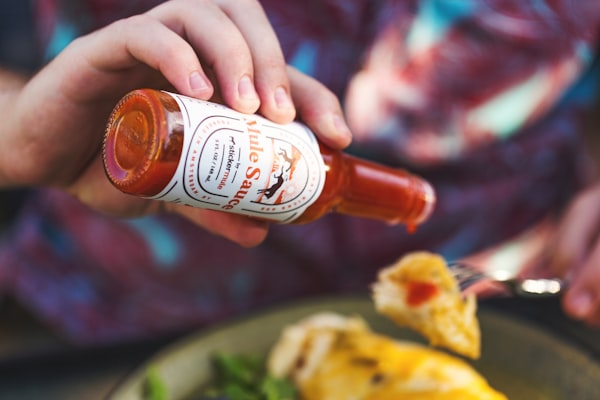 Man dabbing hot sauce onto food.