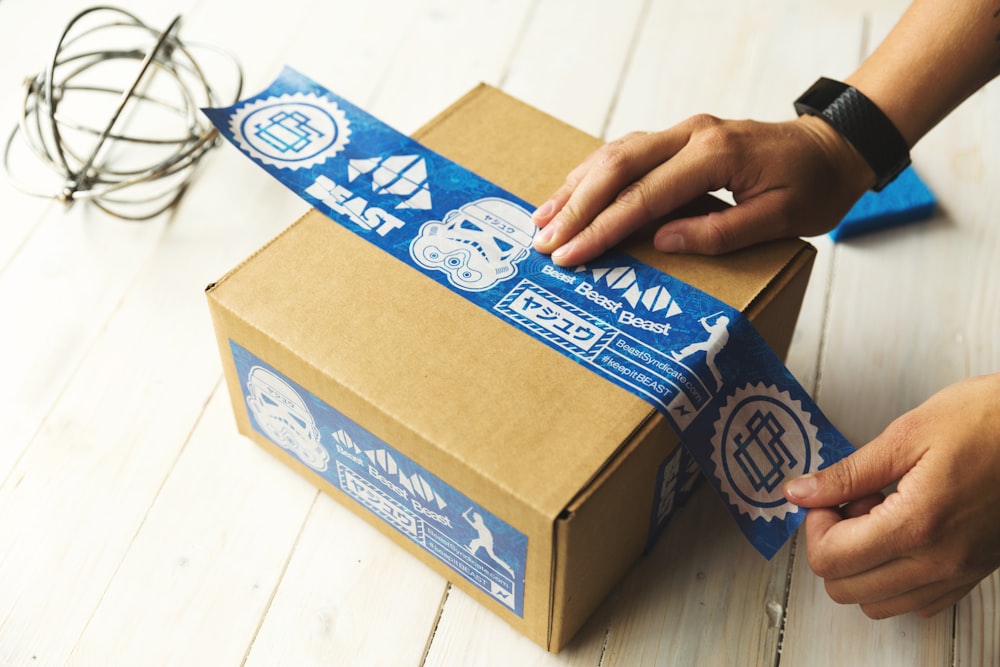 Persona sosteniendo una caja marrón y azul