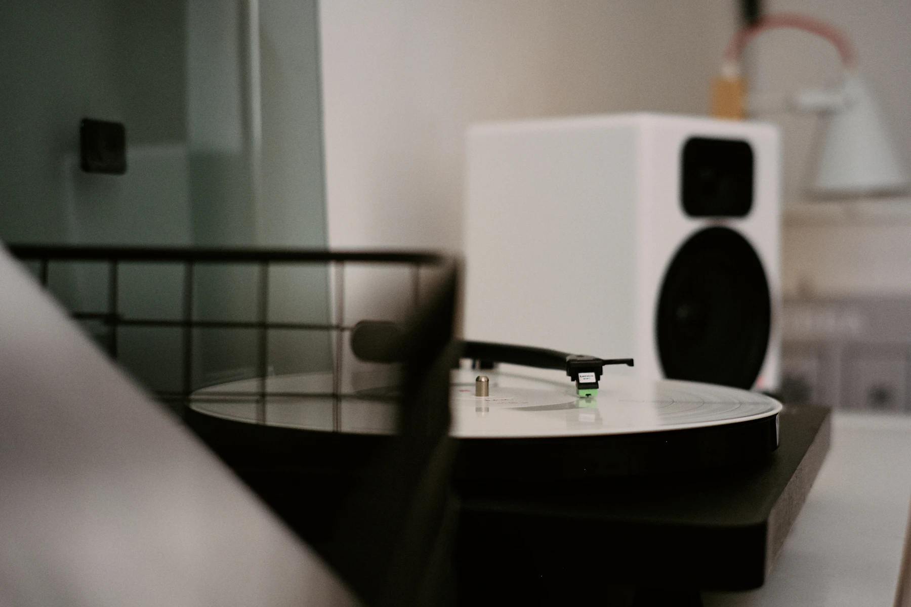 Compact black and white speaker positioned beside a turntable