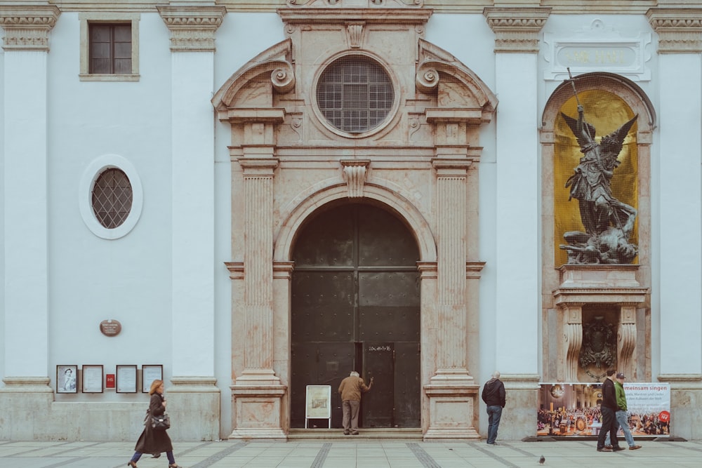 man in black jacket walking near brown wooden door during daytime