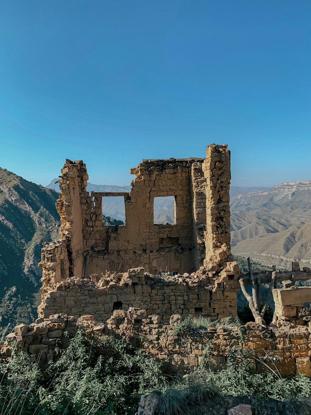 Edificio de hormigón marrón cerca de la montaña bajo el cielo azul durante el día