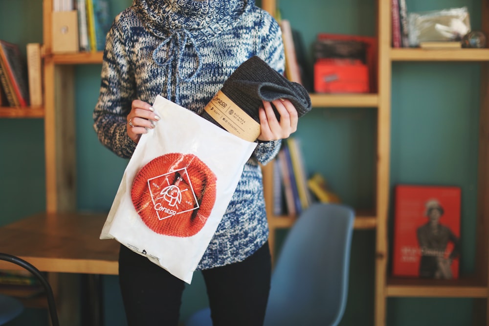 woman in gray and black sweater holding white paper