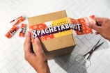 person holding orange and white labeled pack
